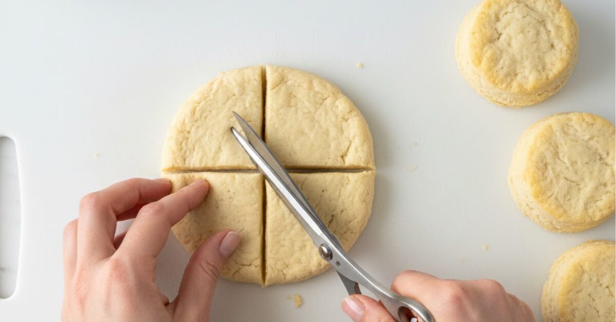 Hands cutting refrigerated biscuit dough into quarters with scissors for microwave monkey bread recipe tutorial
