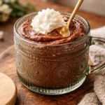 Two servings of egg chocolate pudding in mason jars topped with whipped cream and fresh berries