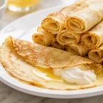 soft zero carb carnivore crepes rolled on a plate with whipped cream