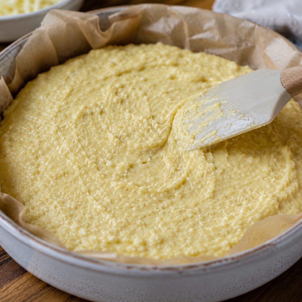 Thick carnivore bread batter being spread in a baking dish